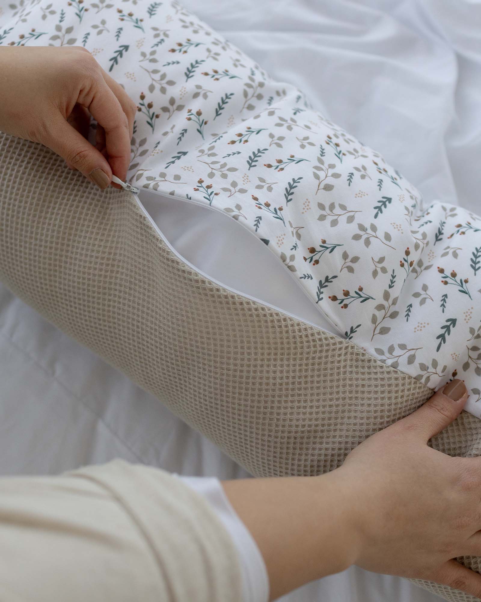 Beige waffle knit nursing pillow cover with a hidden zipper, revealing a white floral pattern.