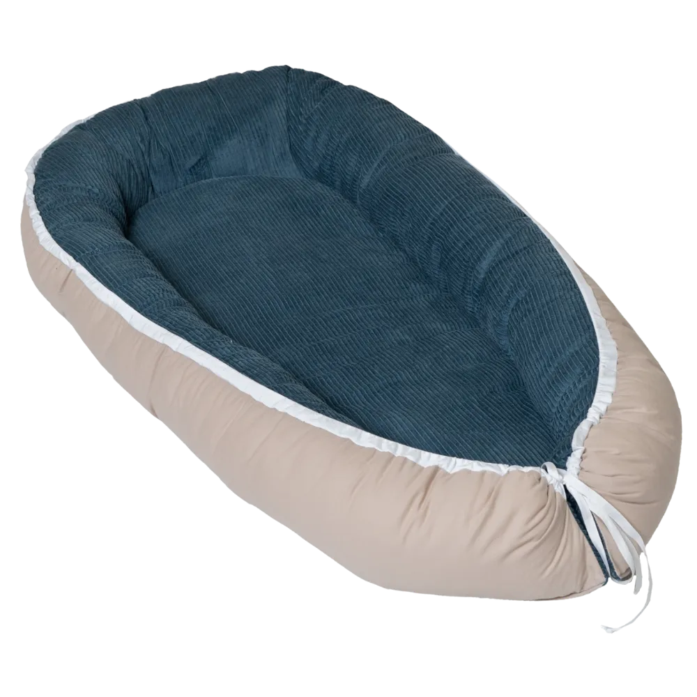 ULLENBOOM Babynest aus petrolfarbenem Cord und beigem Stoff, schräg von oben auf weißem Hintergrund.