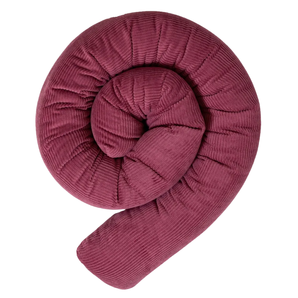 Dunkelrosa Bettschlange aus Cordstoff, spiralförmig aufgerollt, vor weißem Hintergrund.