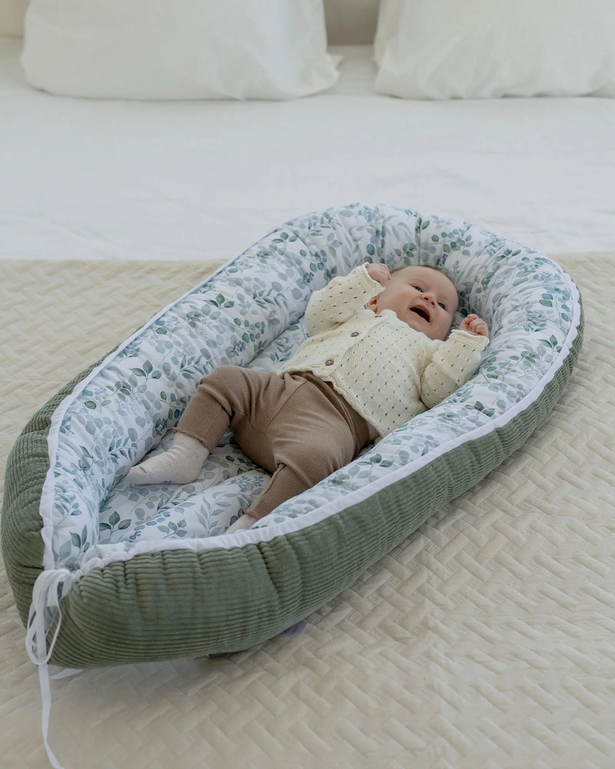 Baby liegt kuschelig im Babynest Cord Eukalyptus