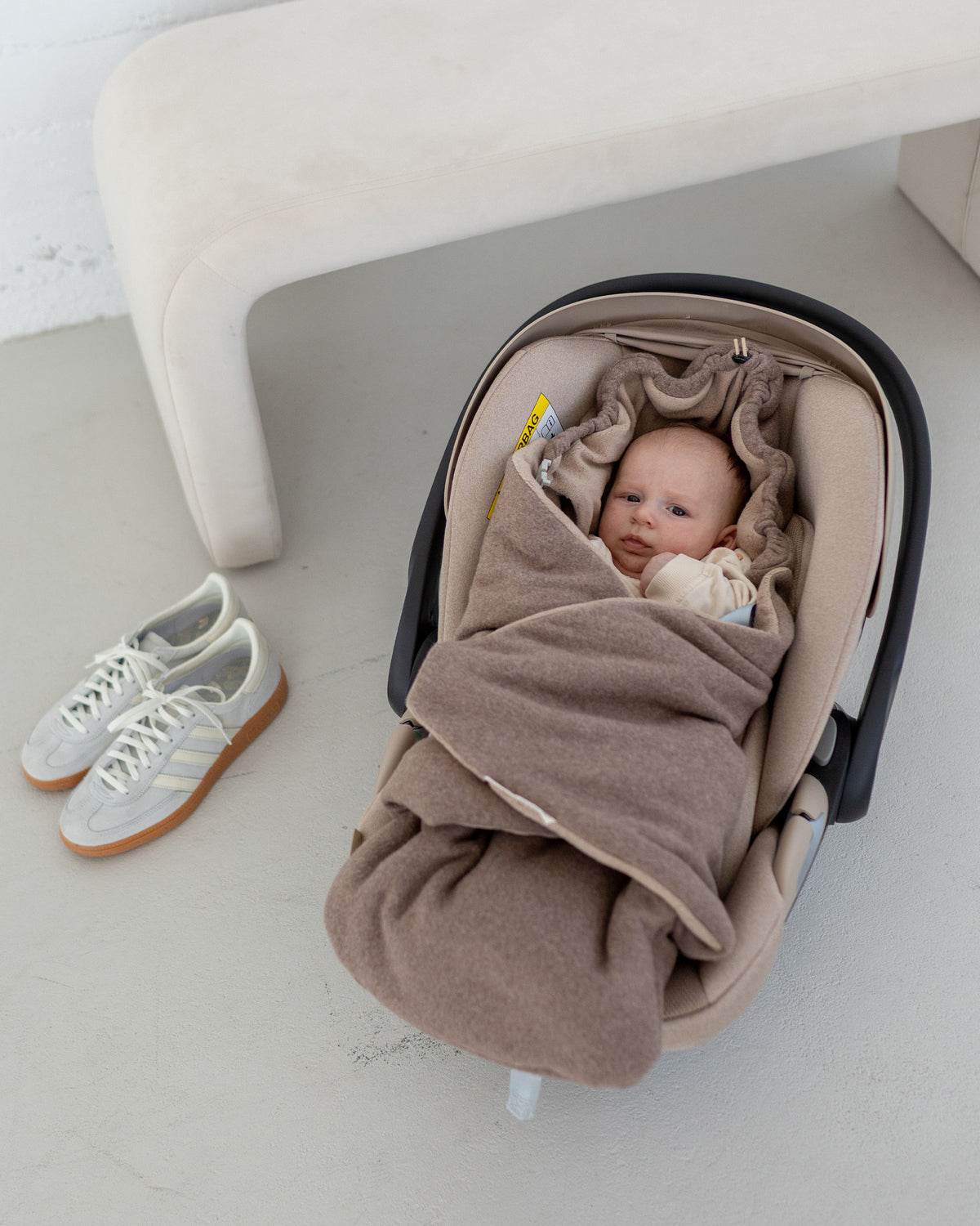 Baby in der Babyschale, eingekuschelt in die Einschlagdecke Fleece Braun