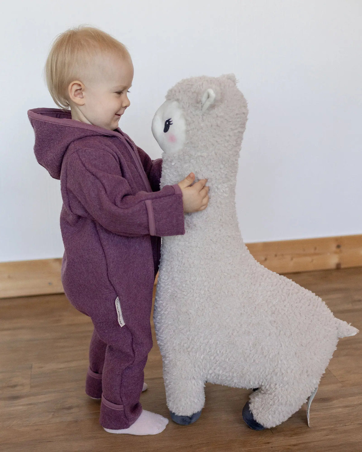 Kind im Wollwalk Overall Beere Größe 74-80 mit Kuscheltier