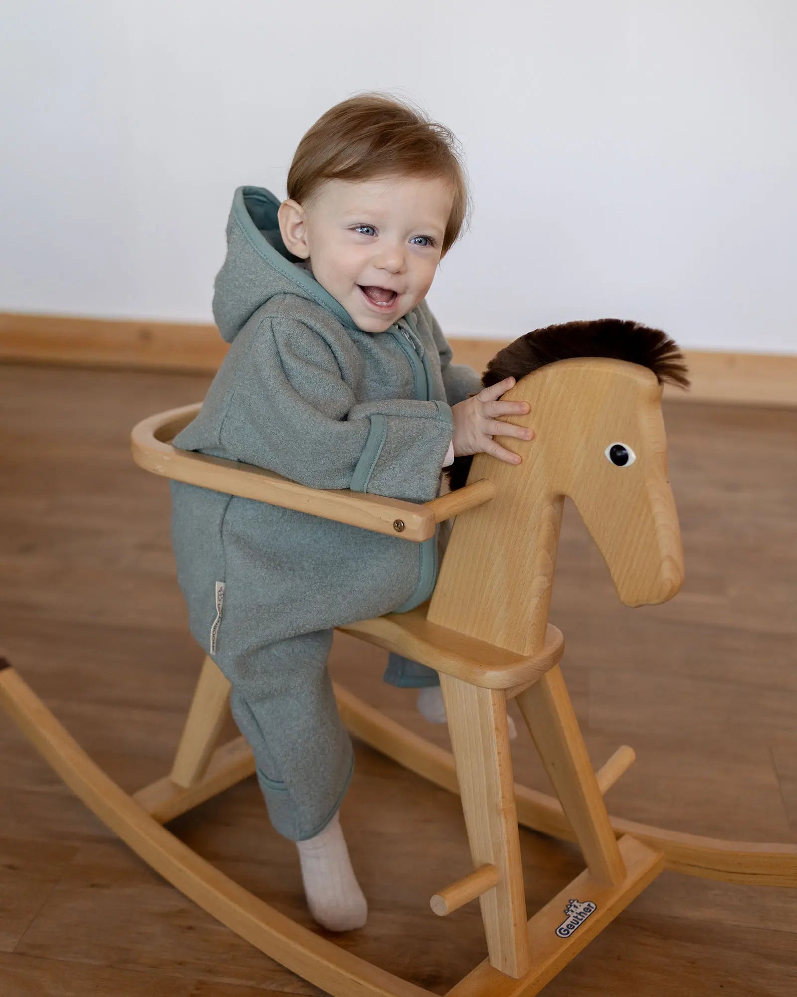 Kind im Wollwalk Overall Eukalyptus Grün mit Kuscheltier