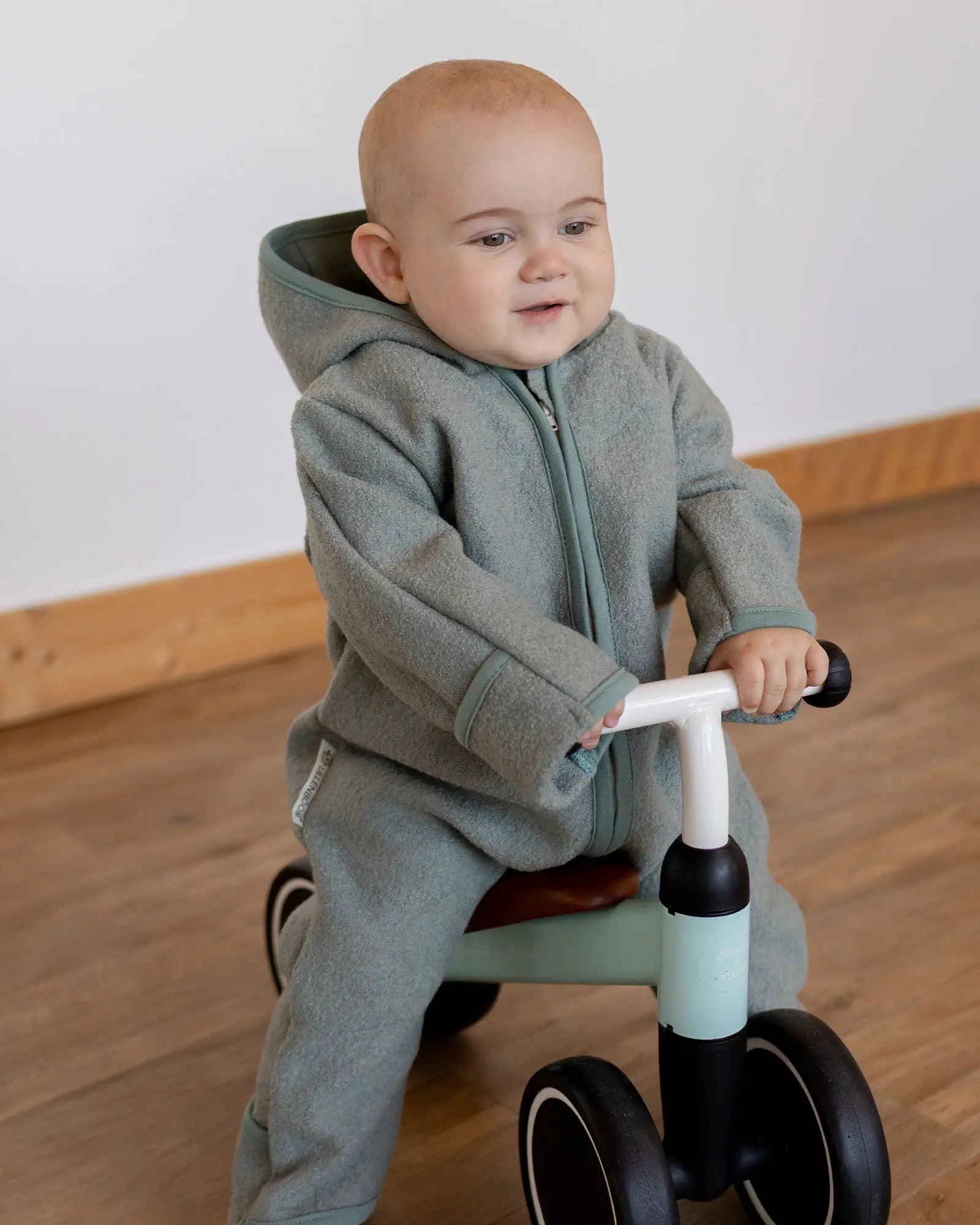 Baby im Wollwalk Overall Eukalyptus Grün in der Babytrage