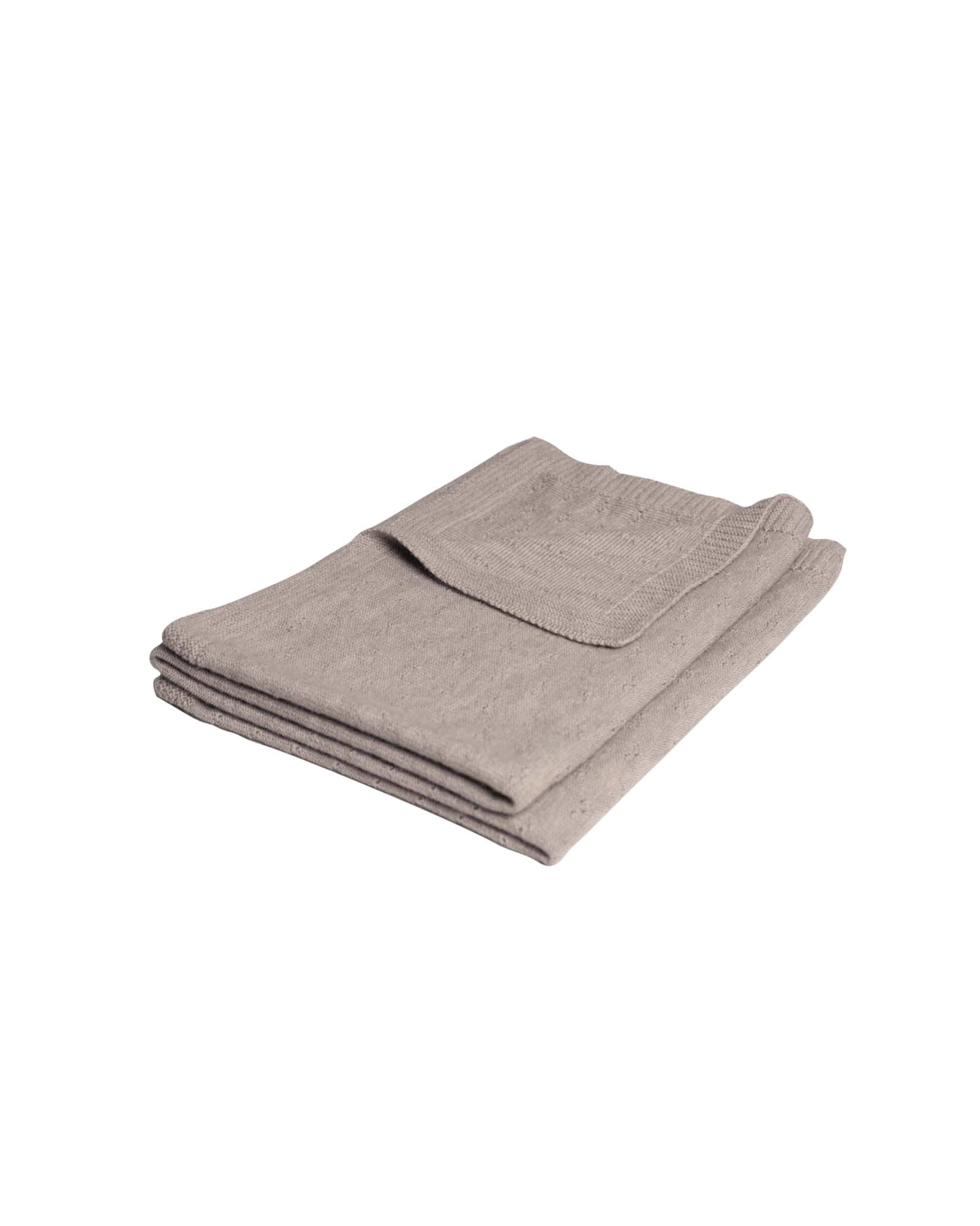 Folded beige merino wool baby blanket with a subtle knit pattern.