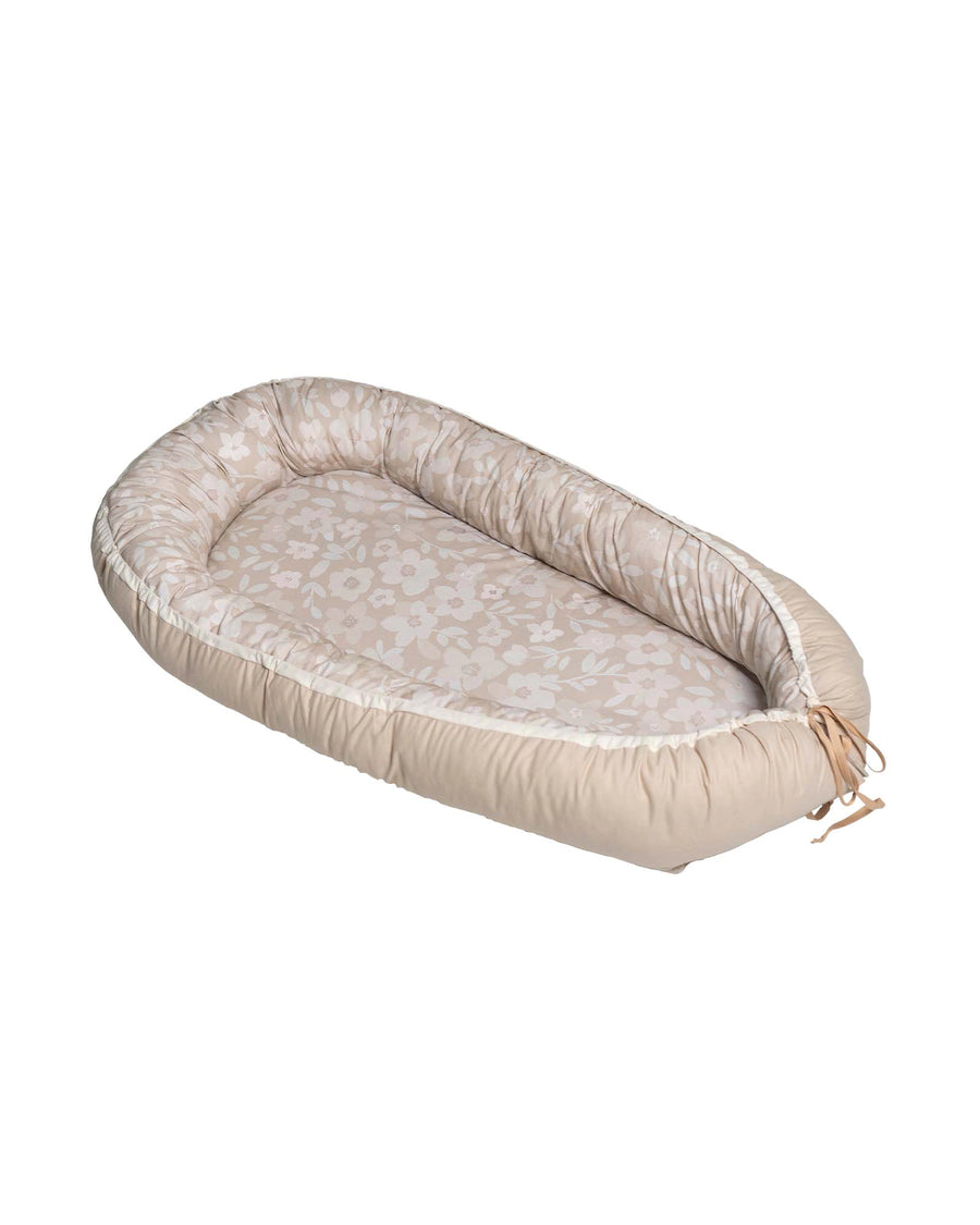 Reversible beige babynest with a floral patterned interior and adjustable ties.