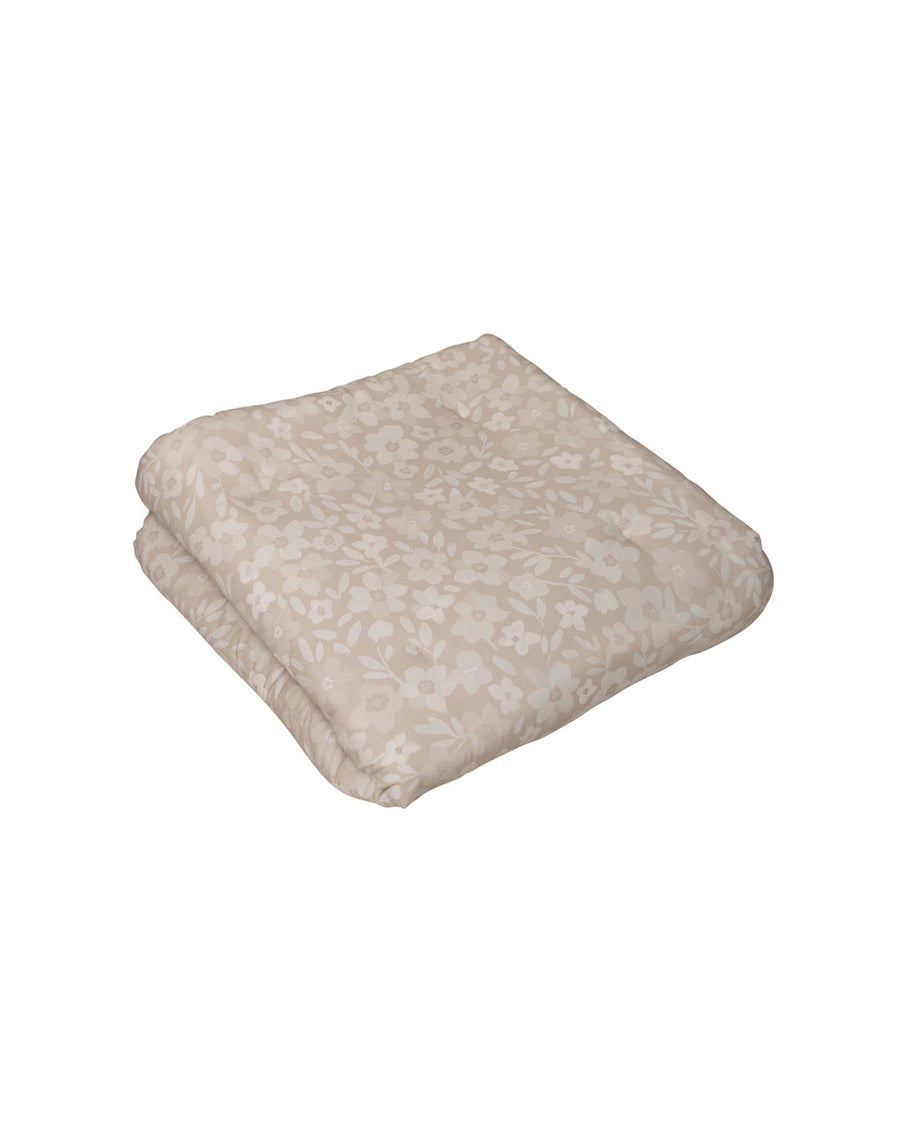 Folded beige cotton baby play mat with delicate white and light pink floral pattern.