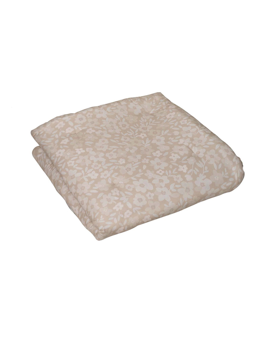 Beige cotton play mat with hand-painted floral pattern, folded.