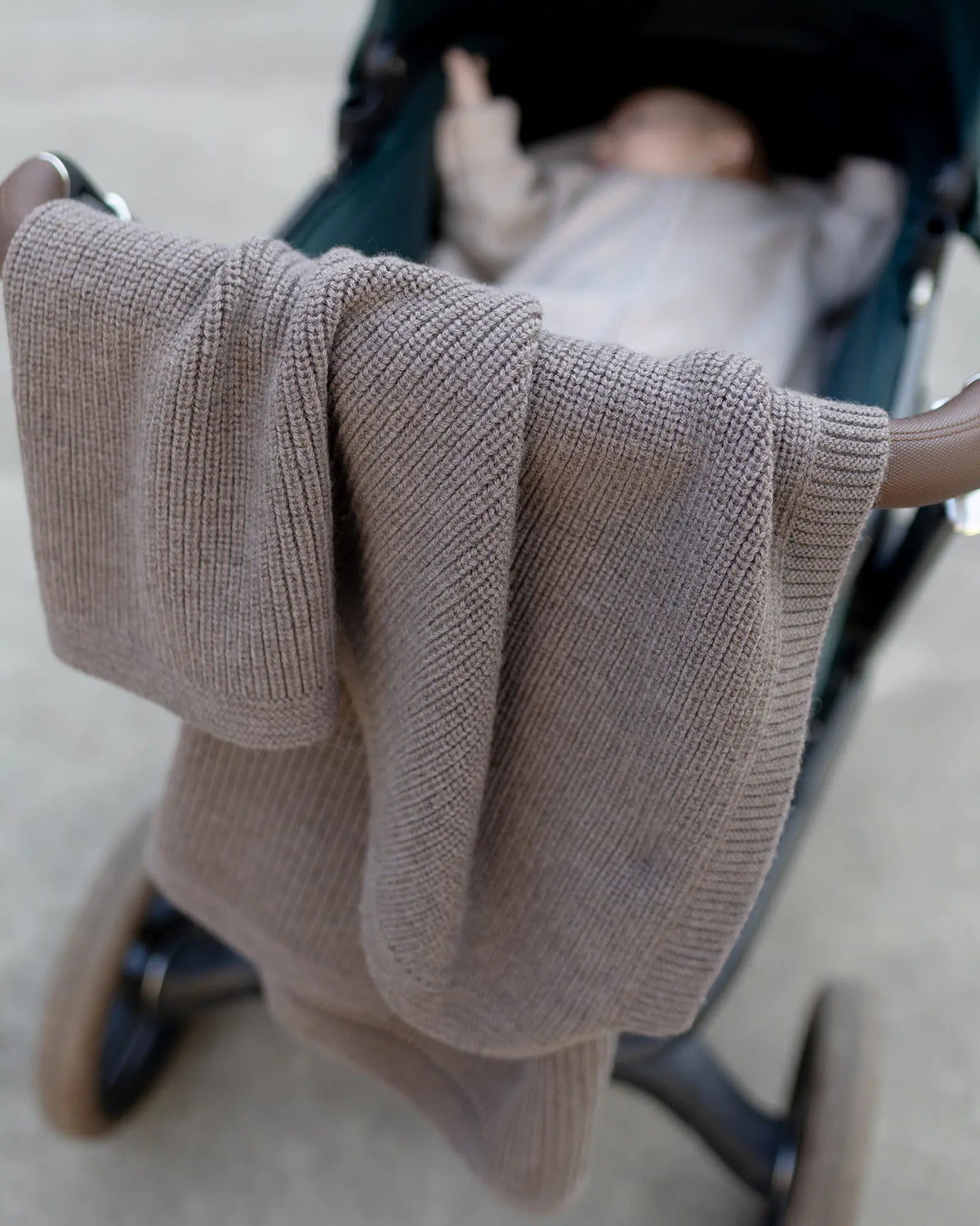 Babydecke Merinowolle Taupe über dem Kinderwagen mit Baby