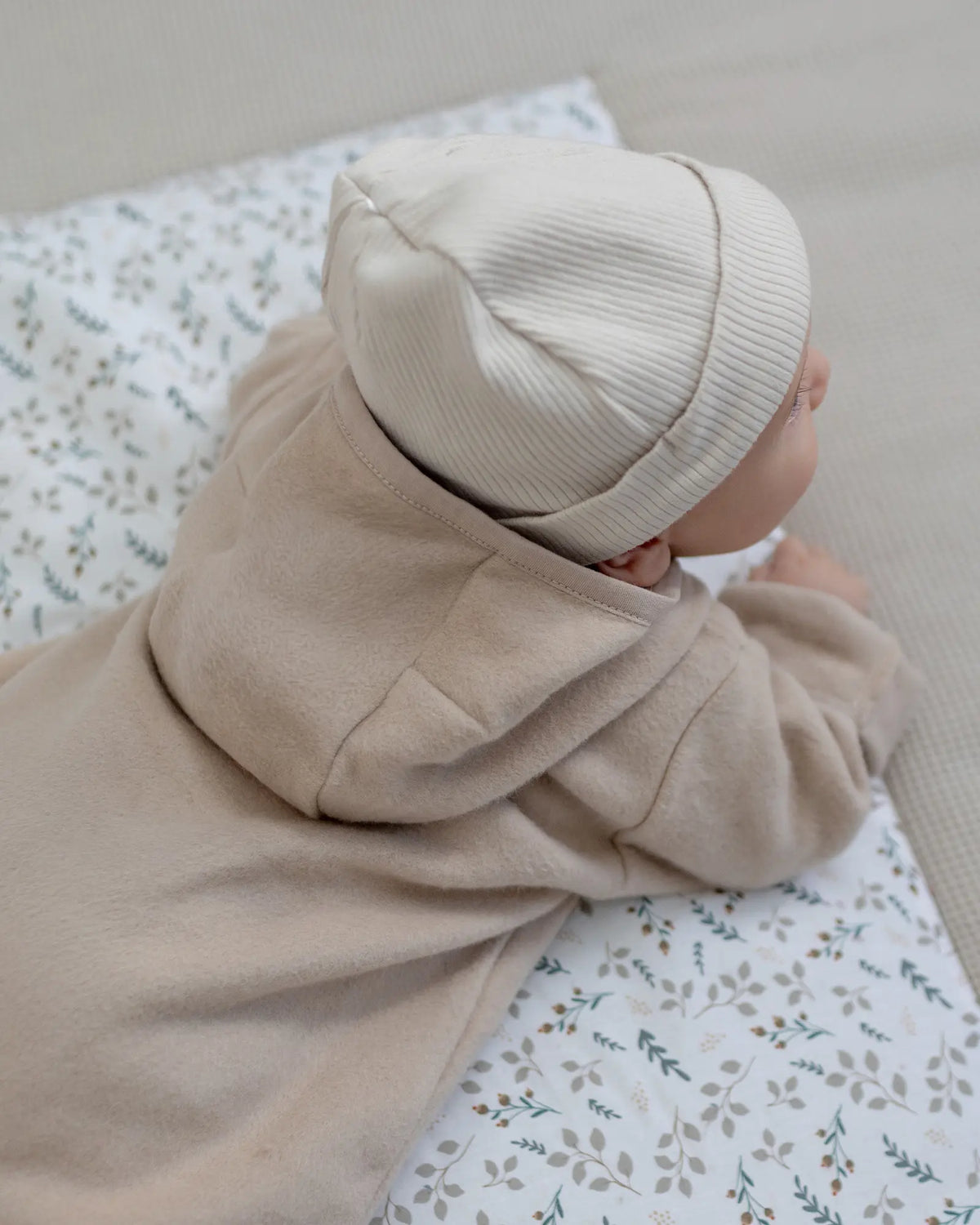 Baby im Baumwoll-Fleece Overall Hafer Beige von hinten mit Kapuze