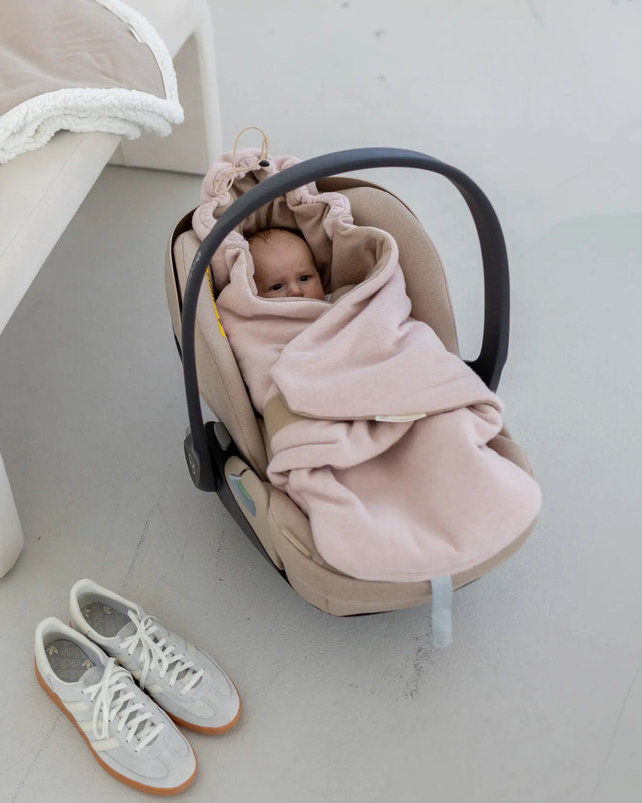 Baby in der Babyschale, eingekuschelt in die Einschlagdecke Fleece Rosa