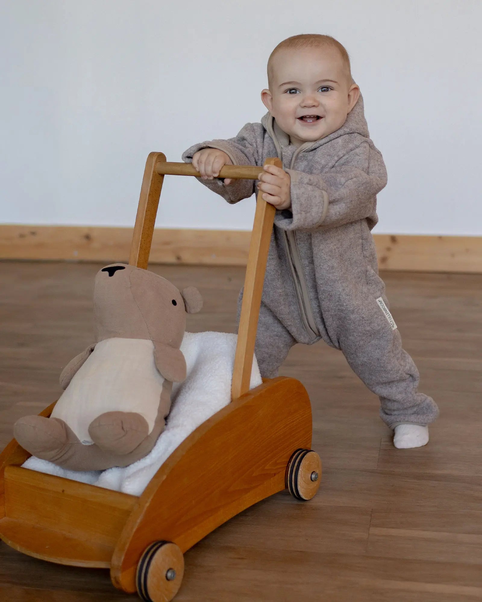 Kind im Wollwalk Overall Hafer Beige mit Kuscheltier